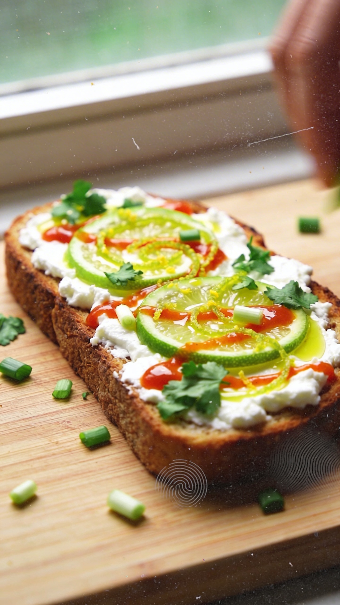 A real-looking photo of a cozy kitchen breakfast scene featuring a toasted piece of sturdy bread topped with cottage cheese, a bright swirl of lime juice and zest, a drizzle of Sriracha or chili crisp, chopped cilantro and scallions, all arranged in a casual, imperfect way on a wooden cutting board. The scene should reflect the “9. Spicy Sriracha Lime Burst” vibe: bold, zippy colors with the lime-green pop contrasting against white cottage cheese and the red-orange Sriracha. Shoot with natural window light, slight overexposed highlights in spots, a few lens specks, and a gentle, imperfect balance of shadows. The photo should feel like an everyday, unstaged moment—no staging, no obvious editing signs, just a quick shot taken in a hurry. Include realistic phone-camera imperfections: slight motion blur from a casual hand, a tilted horizon, perhaps a fingerprint on the lens, and a grainy texture that varies with light. The image should look like an authentic iPhone photo, compressed, 1080p quality, with no text overlays or captions. Optional subtle, believable post-processing hints: a small, subtle color shift or gentle sharpening that keeps it natural. No words or branding visible.