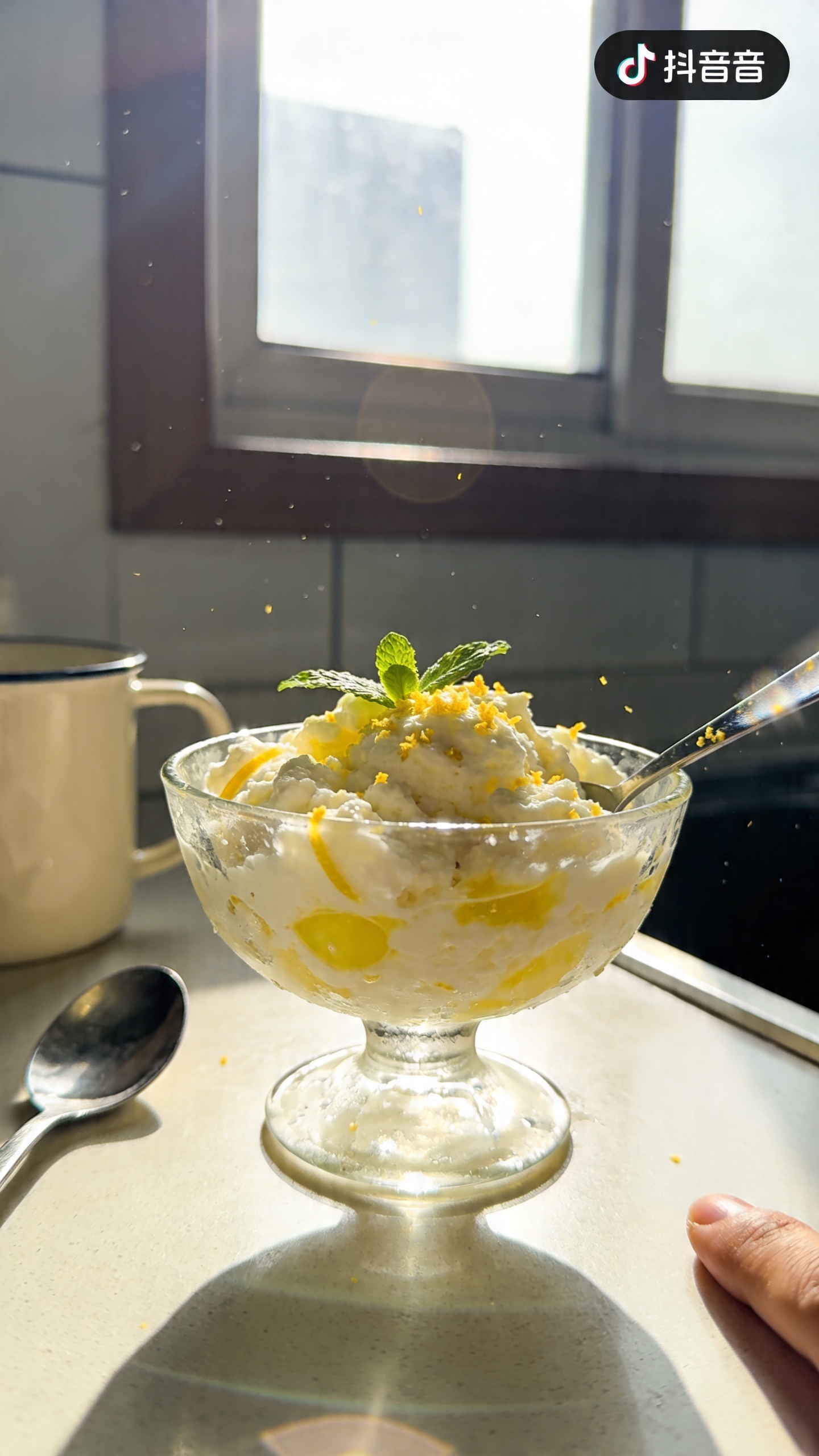 A real, authentic photo of a bowl of cottage cheese lemon zest sherbet, photographed on an iPhone as if taken casually in a home kitchen. The scene features a glass, slightly imperfect dessert bowl filled with creamy cottage cheese sherbet, bright lemon juice and zest visible, a few fresh mint leaves on top, and a light dusting of zest. The background is a cozy kitchen counter with natural window light streaming in, casting gentle shadows. The composition is casual and slightly imperfect: the bowl sits off-center, a mug and a spoon nearby, a finger or stray hand in the frame as if someone just set the bowl down. Subtle, natural lens flare from the window, a touch of overexposed highlights on the glossy surface of the sherbet, and a tiny tilt to the horizon. Slight motion blur in the edge of the spoon as if just set down, minor grain from the lighting, and a compressed 1080p feel with no staging. No words on the image. Optional subtle post-processing hints: hint of gentle color tweak and slight sharpening to mimic a real phone photo. Shot quickly, no professional setup, finger‑print on lens and a casually imperfect vibe to convey a fresh, palate-cleansing dessert.
