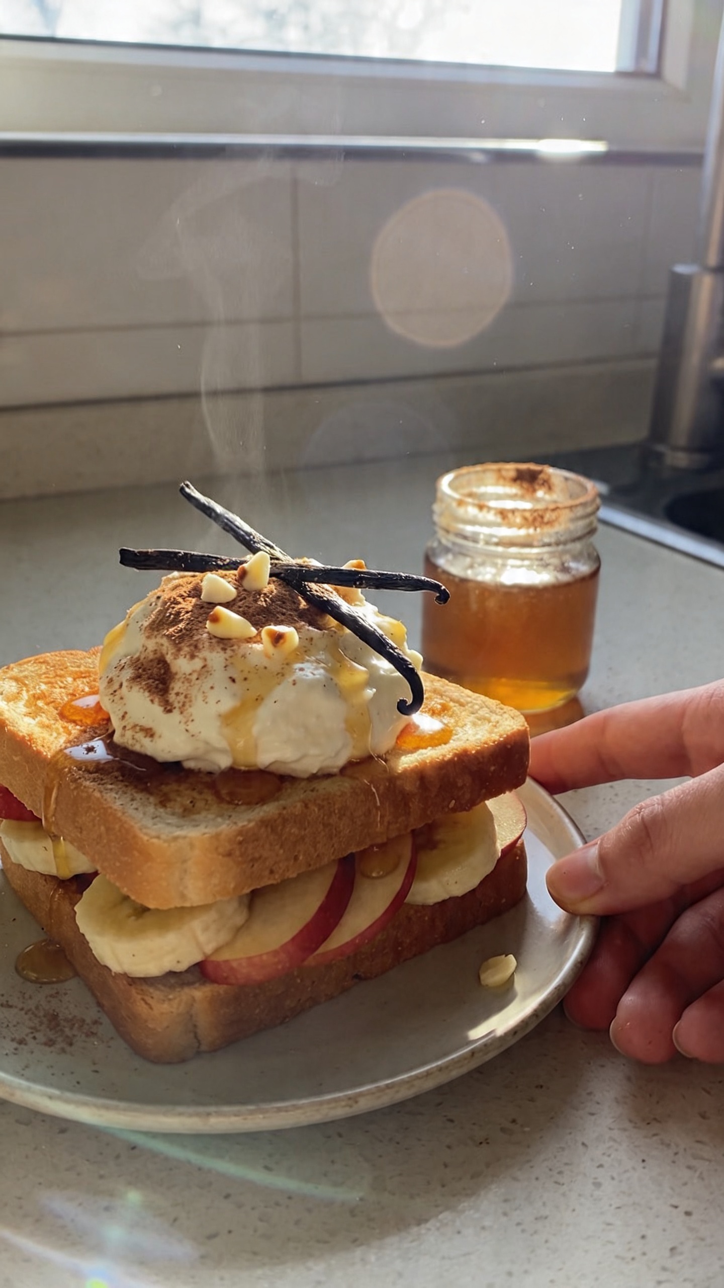 A real, authentic photo of a sweet cinnamon–vanilla cottage cheese breakfast sandwich on whole-grain or brioche bread, lightly toasted, featuring a dollop of cottage cheese with a dusting of ground cinnamon, a few vanilla bean specks, and a drizzle of honey. Include thin apple slices or banana rounds peeking out, with the sandwich placed on a casual kitchen counter beside a small jar of honey and a light sprinkle of cinnamon. Use natural window light to create soft, warm tones. Composition should be candid and imperfect: slightly off-center, a hint of steam, fingertips or a hand reaching toward the plate, and a casually arranged setting that looks like a quick, no-staging breakfast. Capture minor imperfections: slight overexposed highlights on the fruit and bread, faint lens flare from the window, tiny motion blur from a quick hand movement, subtle grain variation from the lighting, and a slightly tilted horizon. The image should feel like a real iPhone photo taken in a hurry, with no text, no cinematic or studio cues, and no AI-detectable enhancements beyond light post-processing that keeps it near “scaled down and up again, slight smart blur with sharpening, recolored with a flat paint bucket” vibe for a natural, real-world look. Composed to emphasize the dessert-like, mid-morning treat essence. The subject is the sweet cinnamon–vanilla cottage cheese sandwich. Shot quickly, no staging, fingerprint on lens, compressed 1080p quality. No words on the image.
