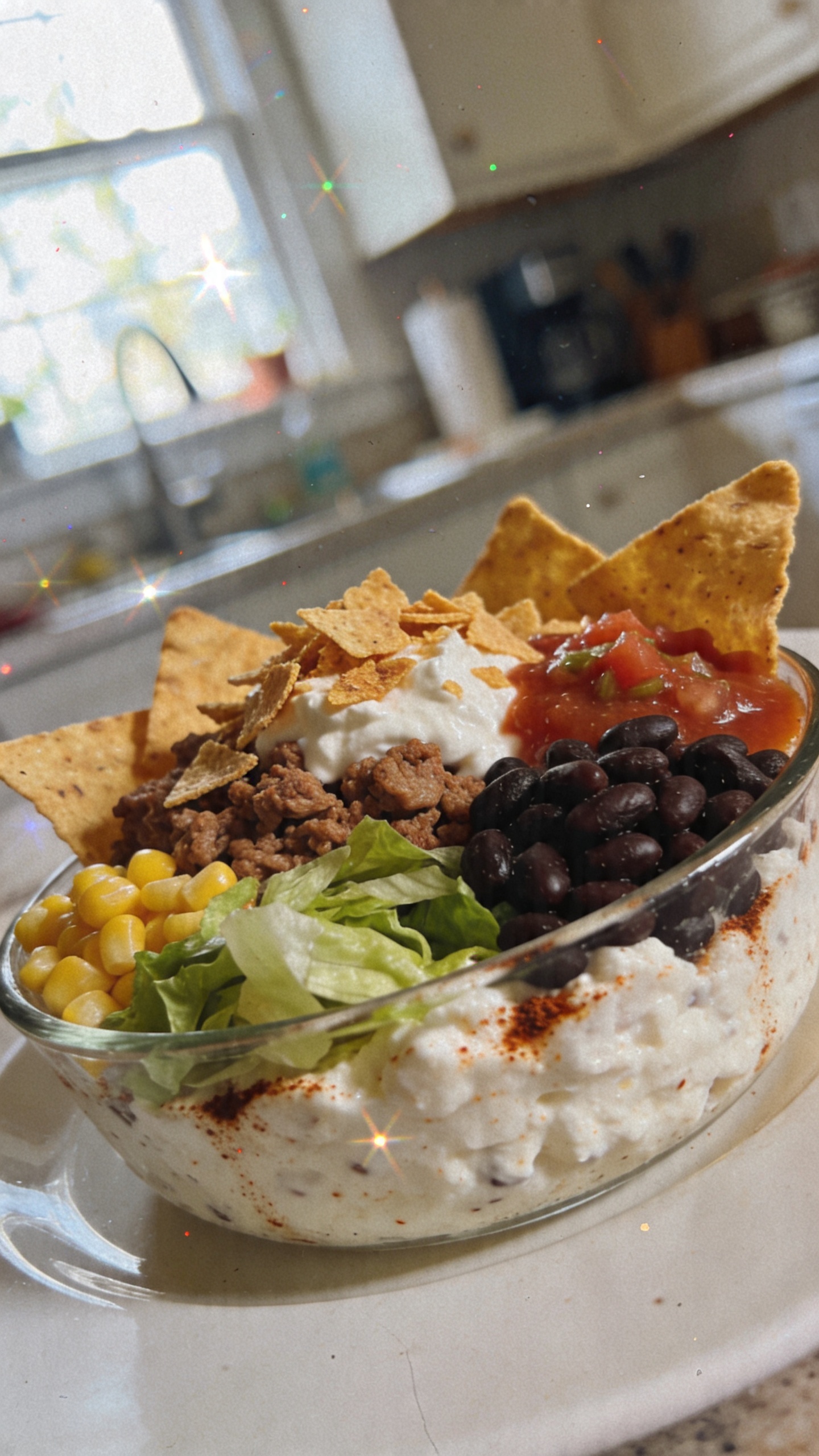 A real, authentic photo of a Crunch-Tub Taco Bowl featuring cottage cheese-based base with taco seasoning, shown as a casual lunch in a bowl with 1 cup cottage cheese, ground turkey or black beans, lettuce, corn, salsa, and crushed baked tortilla chips for crunch; assembled in a relaxed, bite-friendly way with varied textures. shot quickly with natural window light, no staging, casual composition, slightly imperfect, realistic feel. Include realistic phone-camera imperfections: slightly overexposed highlights, subtle lens flare, minor motion blur, grain that varies with light, and a slightly tilted horizon. The main subject should be clearly the bowl of Crunch-Tub Taco Bowl, resembling a candid iPhone photo taken during lunch, with a hint of everyday kitchen environment in the background. No text on the image. Optional subtle post-processing touch: compressed 1080p quality, small blur/sharpen balance to resemble a casual smartphone shot, no obvious AI artifacts. Avoid words like cinematic, 8k, ultra realistic, hyper realistic, professional photography, studio lighting, depth of field, or perfect composition.